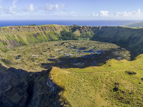 Det runde, gresskledde krateret etter en død vulkan ligger ved klippekanten på en øy.