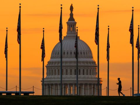 En stor, hvit kuppel ses gjennom amerikanske flagg i solnedgang.