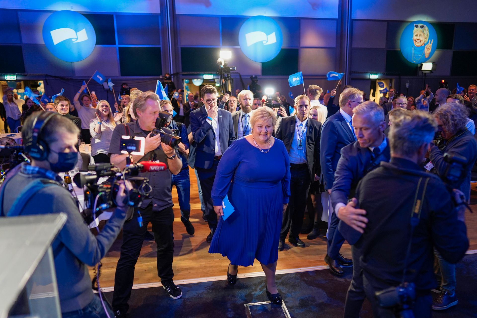 Erna står midt i bildet, omringet av fotografer og journalister som vil få en kommentar etter at hun gikk av talerstolen under Høyres valgvake. 