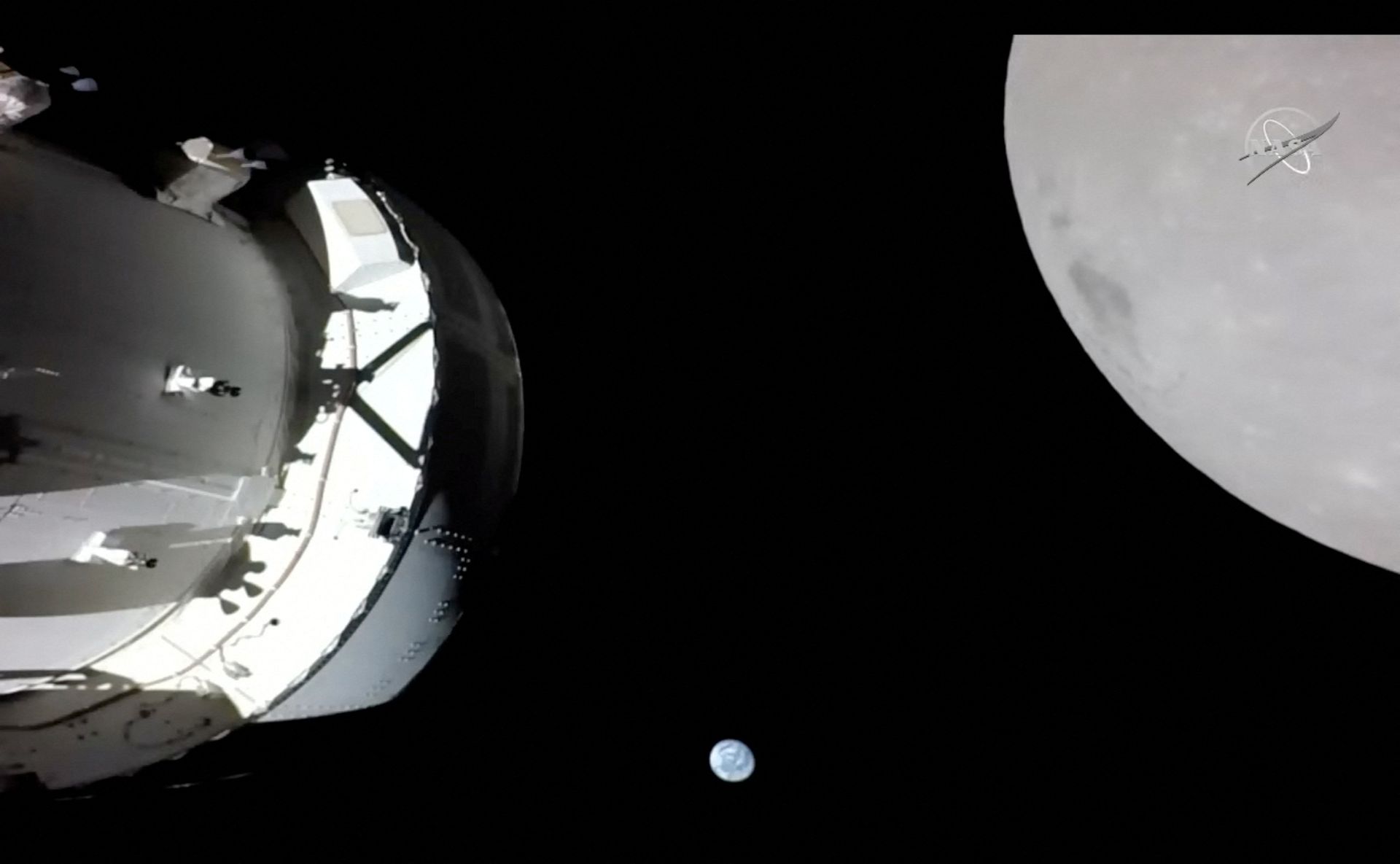 En slags romkapsel svever ved Månen, som er stor og grå, og i midten av bildet, langt unna, synes den lille Jordkloden.