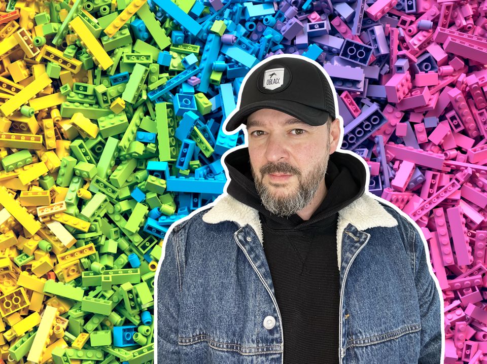 Bilde av en mann med caps og bakgrunnen er lego i forskjellige farger.