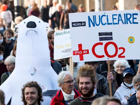 En stor folkemengde marsjerer i gaten med plakater med klima-budskap på, og en stor, oppblåsbar isbjørn med nedoverpekende munn nærmer seg fotografen. 