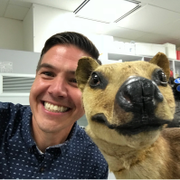En smilende mann sammen med et dyr som ser ut som en hund.
