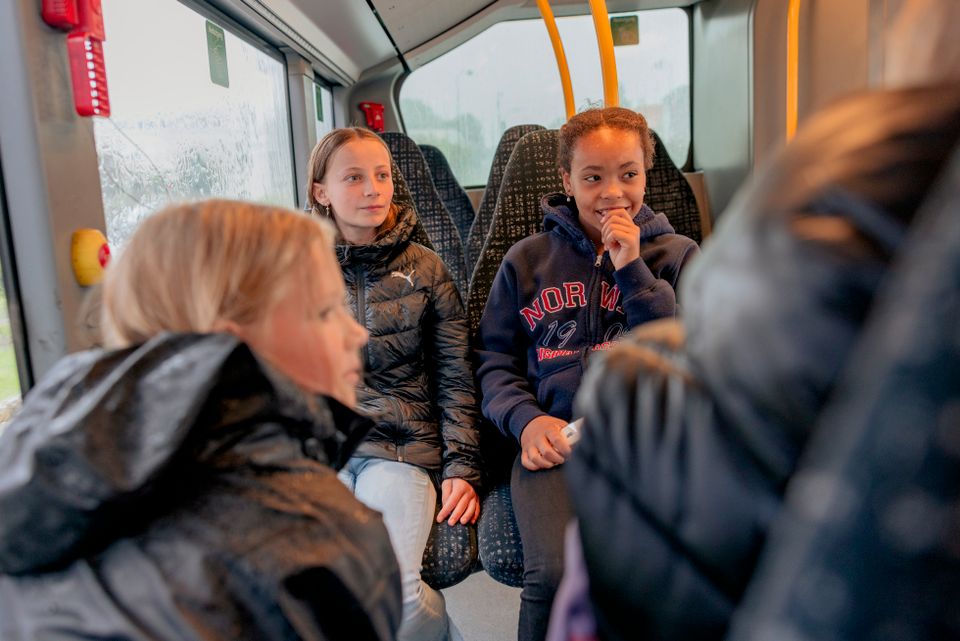 Fire jenter med mørke, tykke ytterjakker på sitter overfor hverandre på en buss.