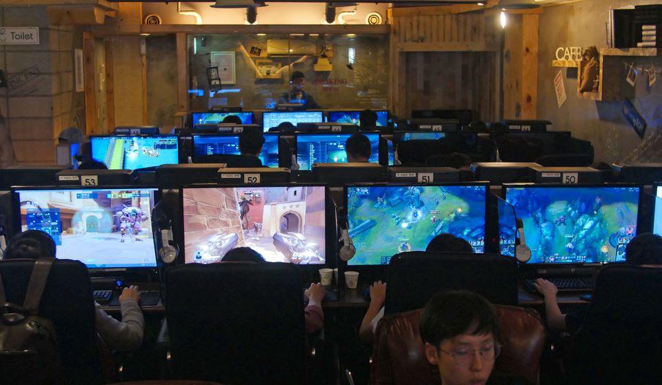 Mange unge mennesker sitter samlet rundt PC-skjermer i et stort lokale.