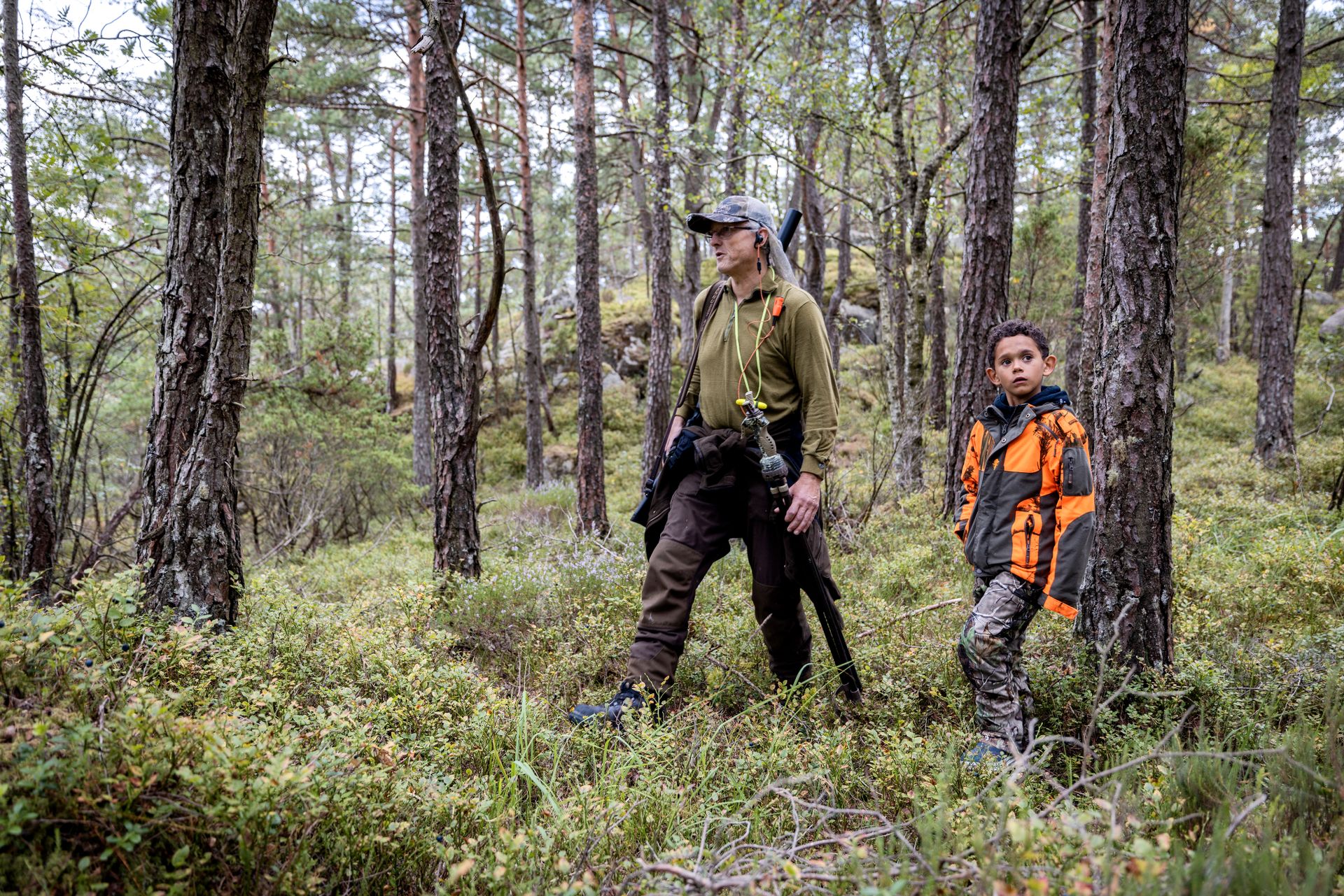 Loke og farfar går mellom trærne i skogen for å finne et nytt sted å speide etter dyr. 