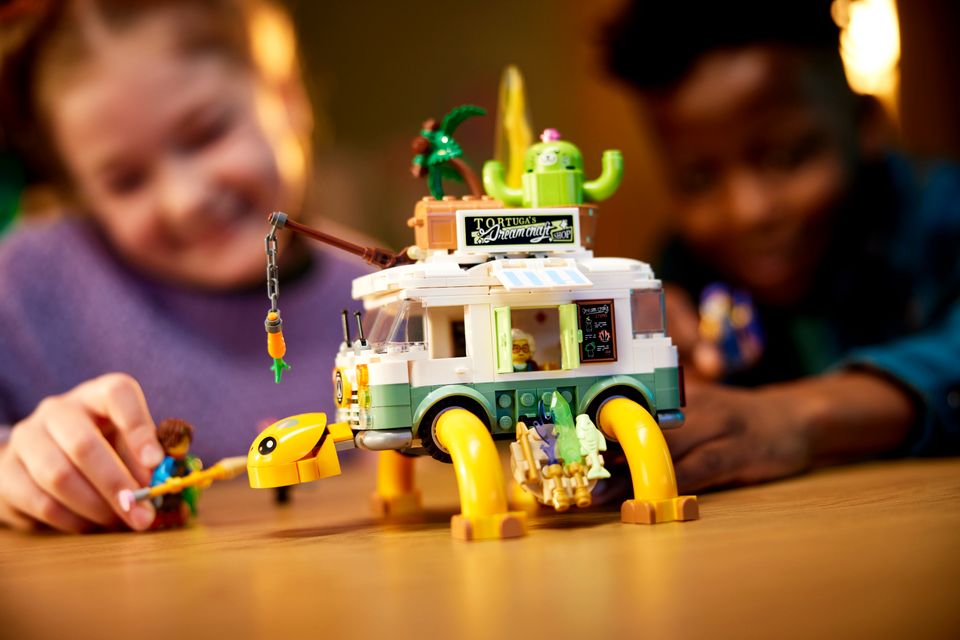 To barn leker med en lego-minibuss som også ser ut som en skilpadde med palme og kaktus på ryggen
