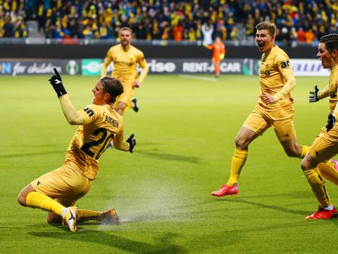 Fire spillere i gule drakter løper over gressbanen på en stadion og jubler, som om de feirer et mål. 