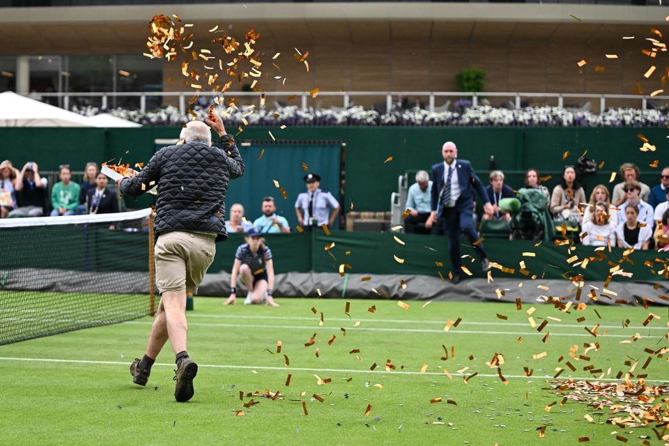 En mann løper ut på en tennisbane med gress og kaster masse konfetti i luften.