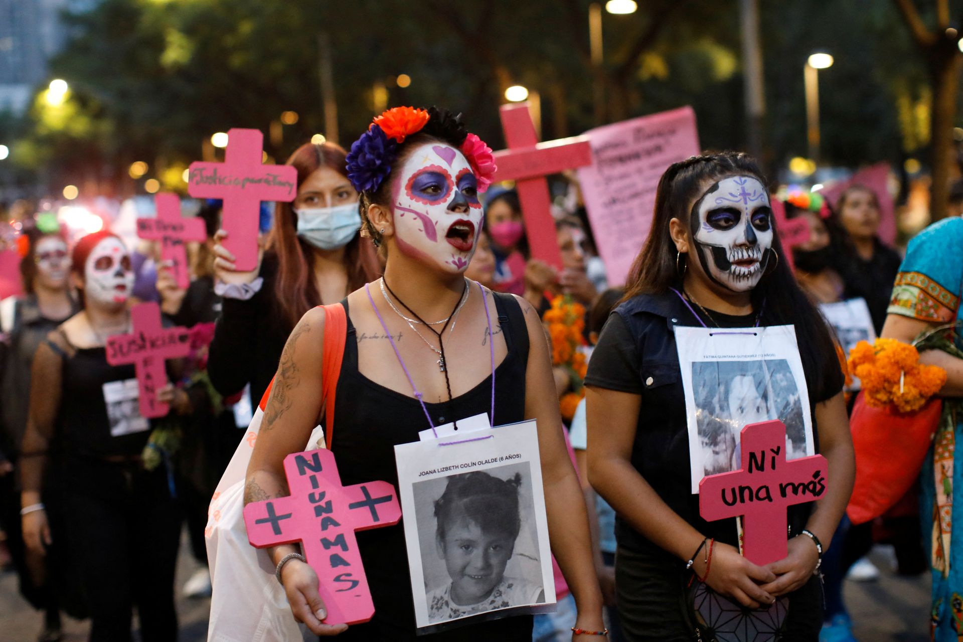 Mange kvinner med hodeskalle-malte ansikter og rosa kors går med hvite plakater av savnede eller drepte kvinner.
