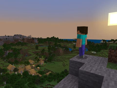 En figur i et spill står oppe på et fjell og kikker utover et landskap.