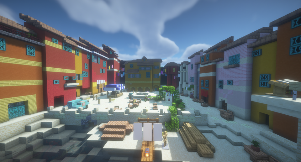 Bilde fra Minecraft av et torg i en by med fargerike hus rundt torget.