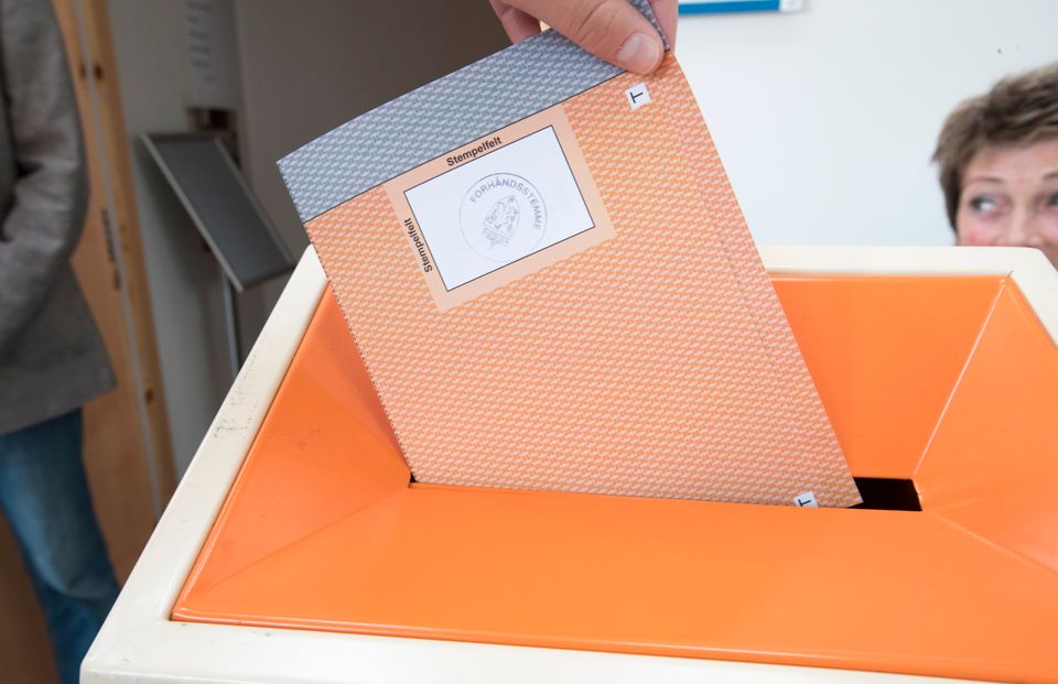 En grå og oransje stemmeseddel blir lagt inn i en oransje stemmeurne.