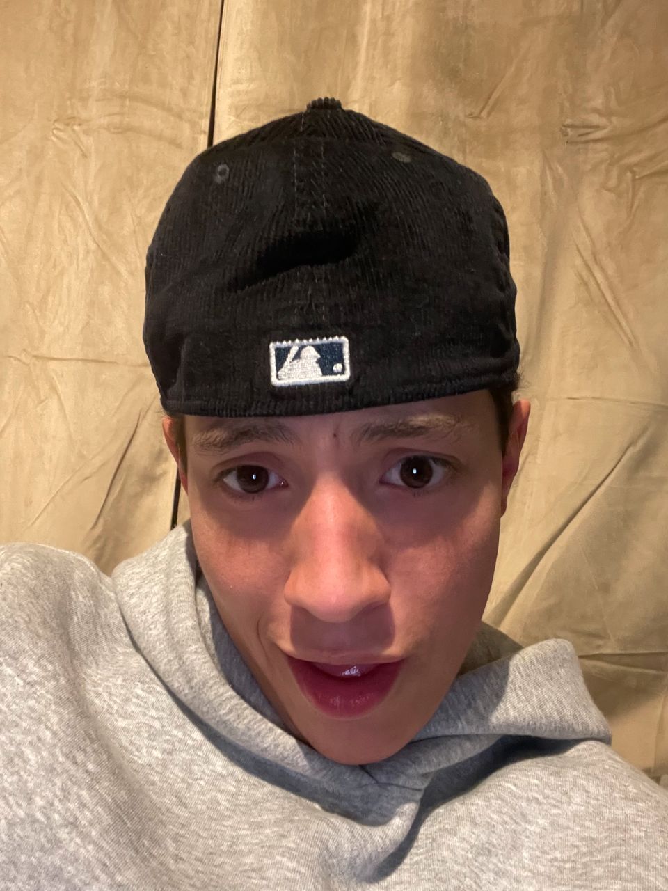 En selfie av en ung mann som har på seg mørk caps og grå hettegenser 