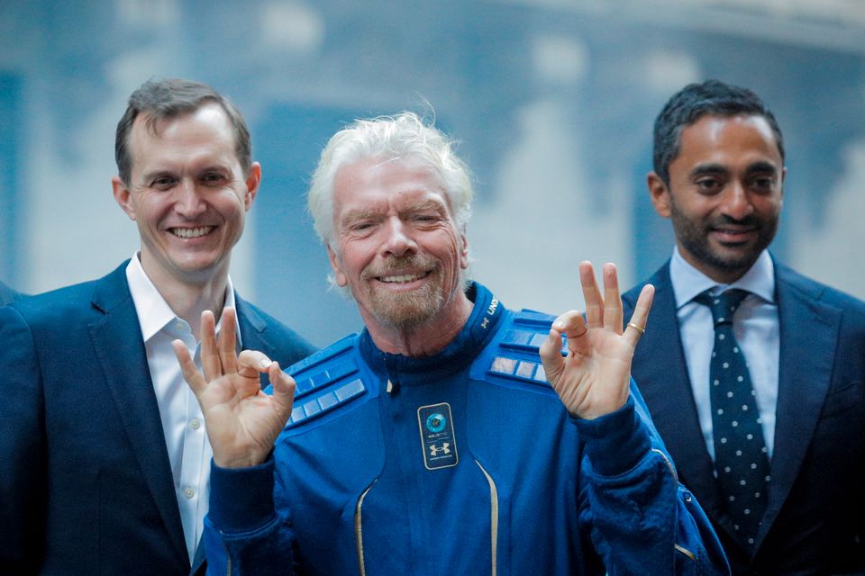 Richard Branson, ikledd en blå romdrakt, viser ok-tegnet med begge hendene etter å ha landet på Jorden igjen, etter sin tur til verdensrommet.