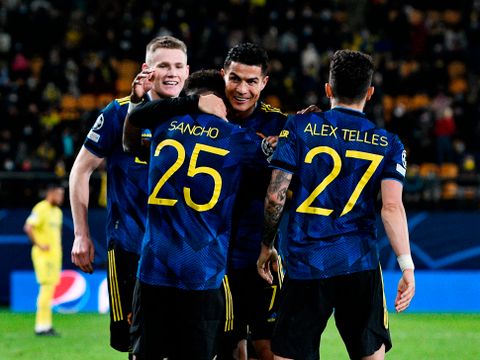 Fire fotballspillere med blå drakter og gule nummer (to av dem med nummer 25 og 27) på ryggen klemmer hverandre på en fotballbane. 