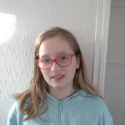 Jente med genser med sommerfugl på og langt glatt hår og briller smiler