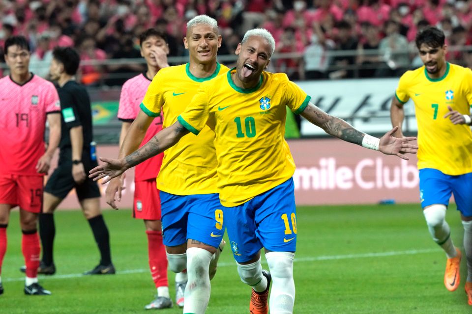 To fotballspillere med gul drakt og blå shorts og bleket hår er glade etter å ha scoret et mål.