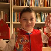 En gutt med rød klær holder en rød konvolutt i den ene hånden og en rød kanin i den andre.