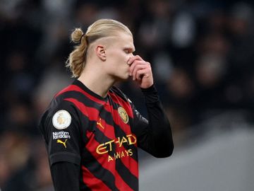En fotballspiller med lyst hår og rød og svart drakt holder seg for nesten og ser skuffet ut.