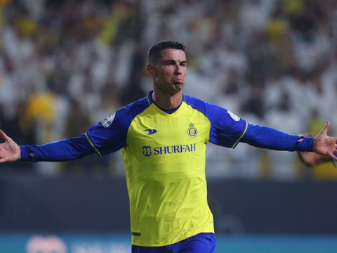 En fotballspiller med svart hår og gul og blå drakt slår ut med armene.