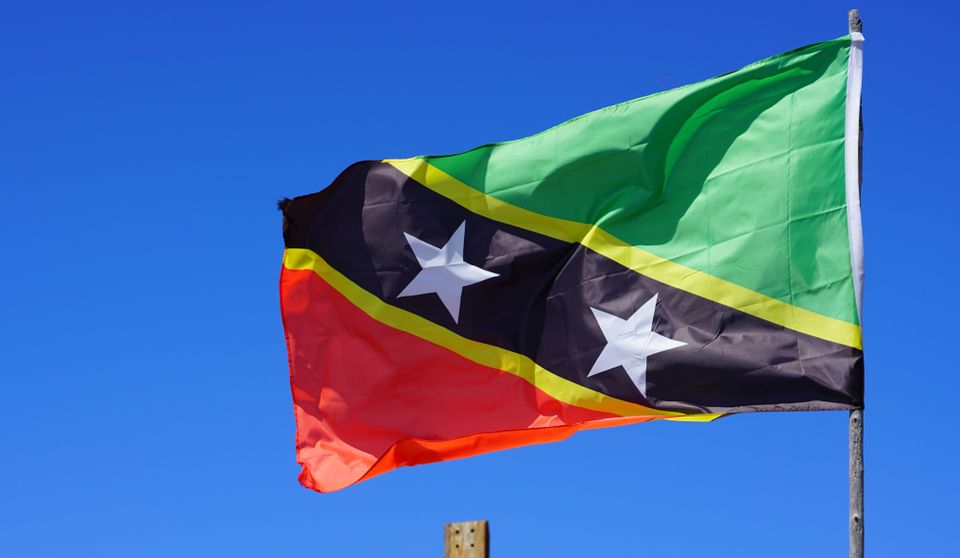 Et rødt, svart og grønt flagg med to stjerner på vaier i vinden.