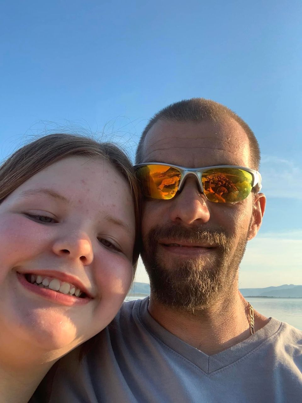 En jente og en mann med solbriller som tar en selfie sammen og smiler. 