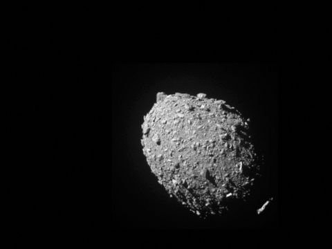 En grå, rund og steinete asteroide er fotografert i helt svarte omgivelser. 