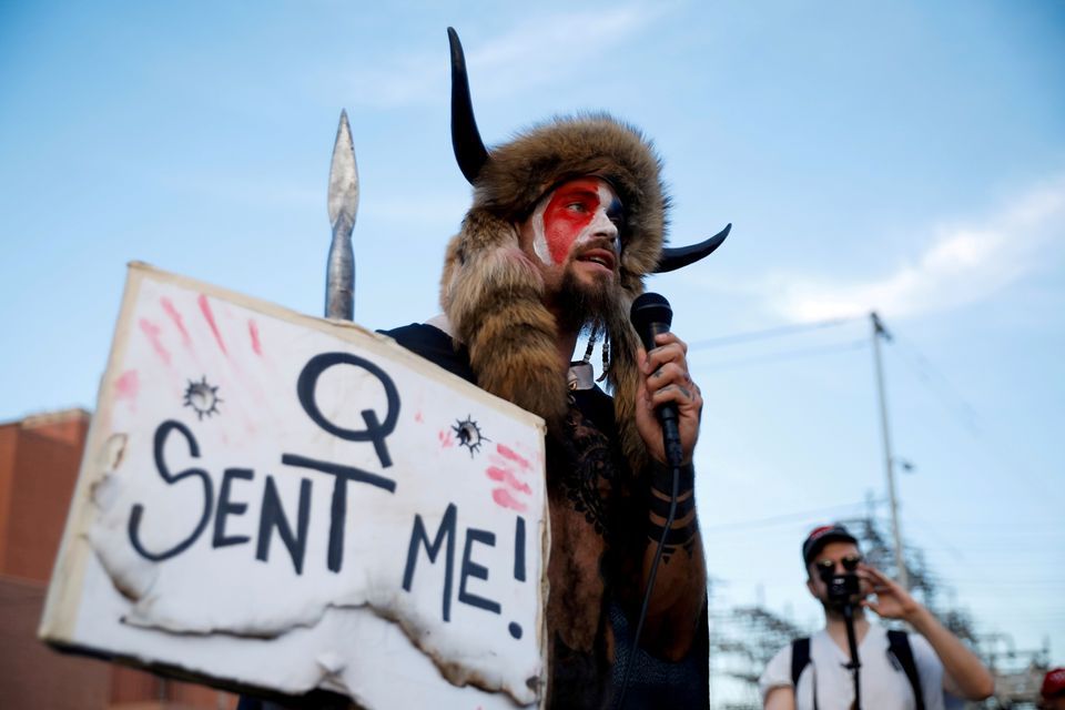 En mann utkledd og med lue med horn holder en plakat.