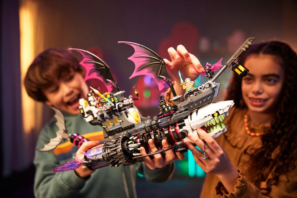 To barn holder et lego-skip som er satt sammen med en hai, dragevinger og motor