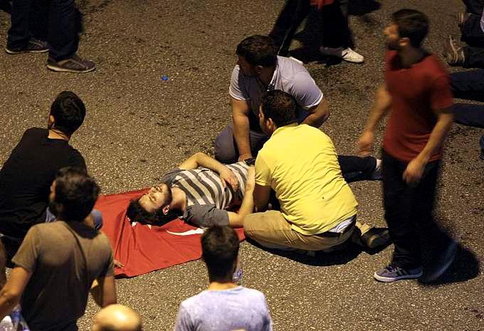 En skadet mann tas hånd om under sammenstøtene i Ankara. Under seg har han Tyrkias flagg.