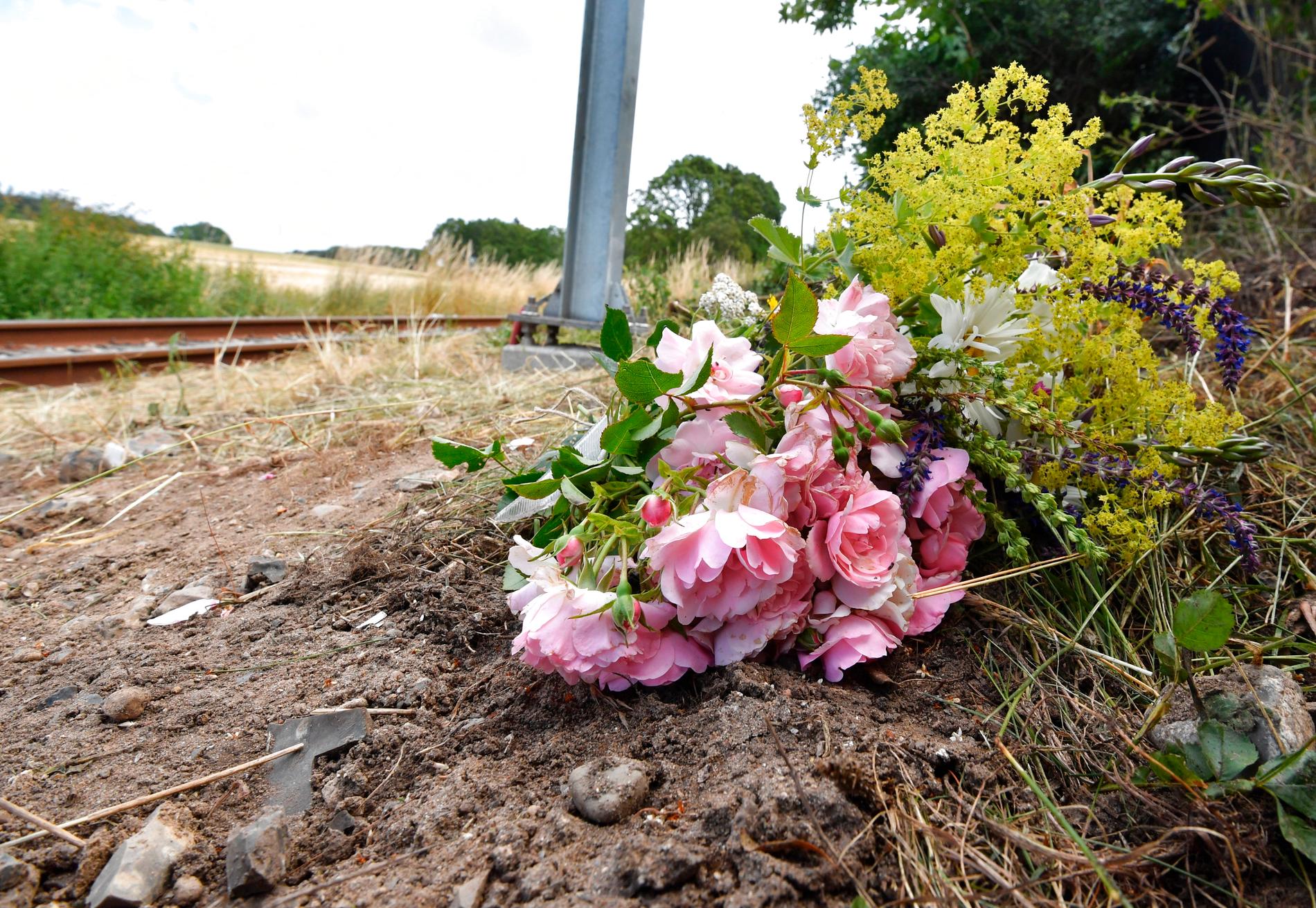 OMKOM: Naboer har lagt ned blomster der en norsk mann og hans sønn mistet livet i en ulykke lørdag mellom en personbil og et letbanetog i Trustrup på Djursland. 