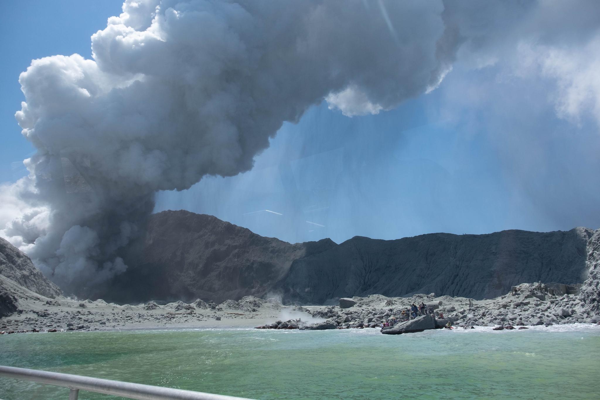 Dette bildet er tatt fra båt av en turist som kort tid før besøkte vulkanøya. Nede til venstre i bildet ses turister som flykter fra utbruddet. De ble senere evakuert med båt. 