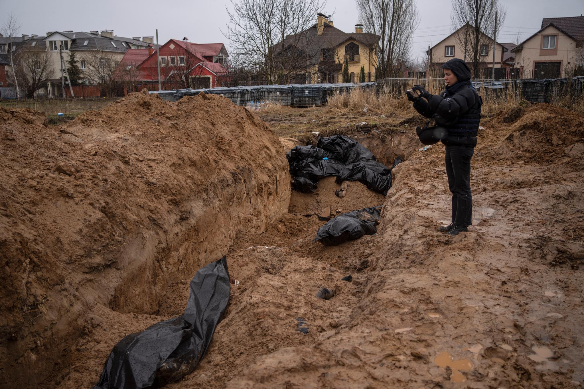 Flere journalister fikk tilgang til byen søndag. Her dokumenterer en av dem en av massegravene.