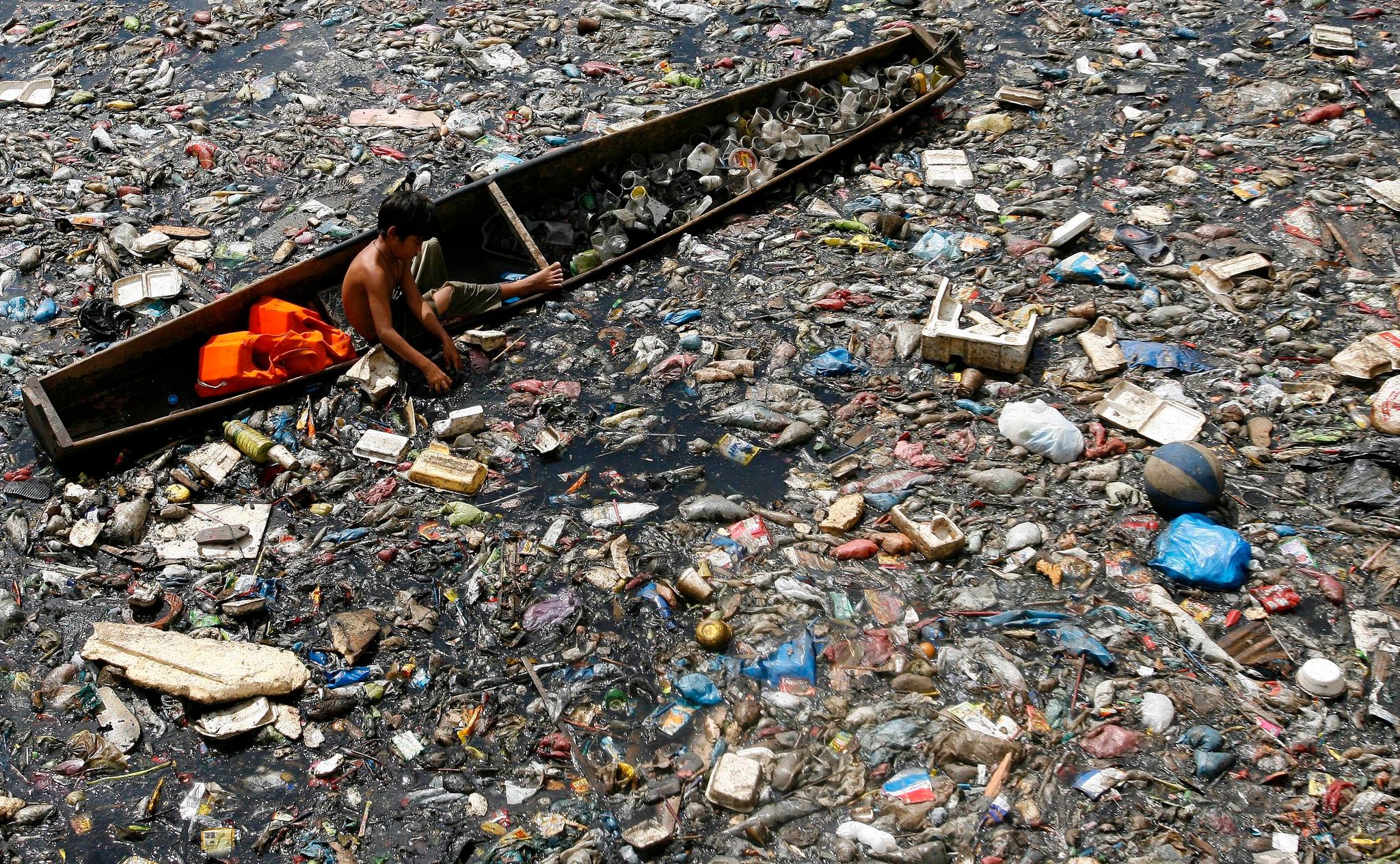En ung gutt leter etter plast han kan selge i elven ved Mandaluyong på Filippinene. Resten blir liggende og flyter ut i havet.
