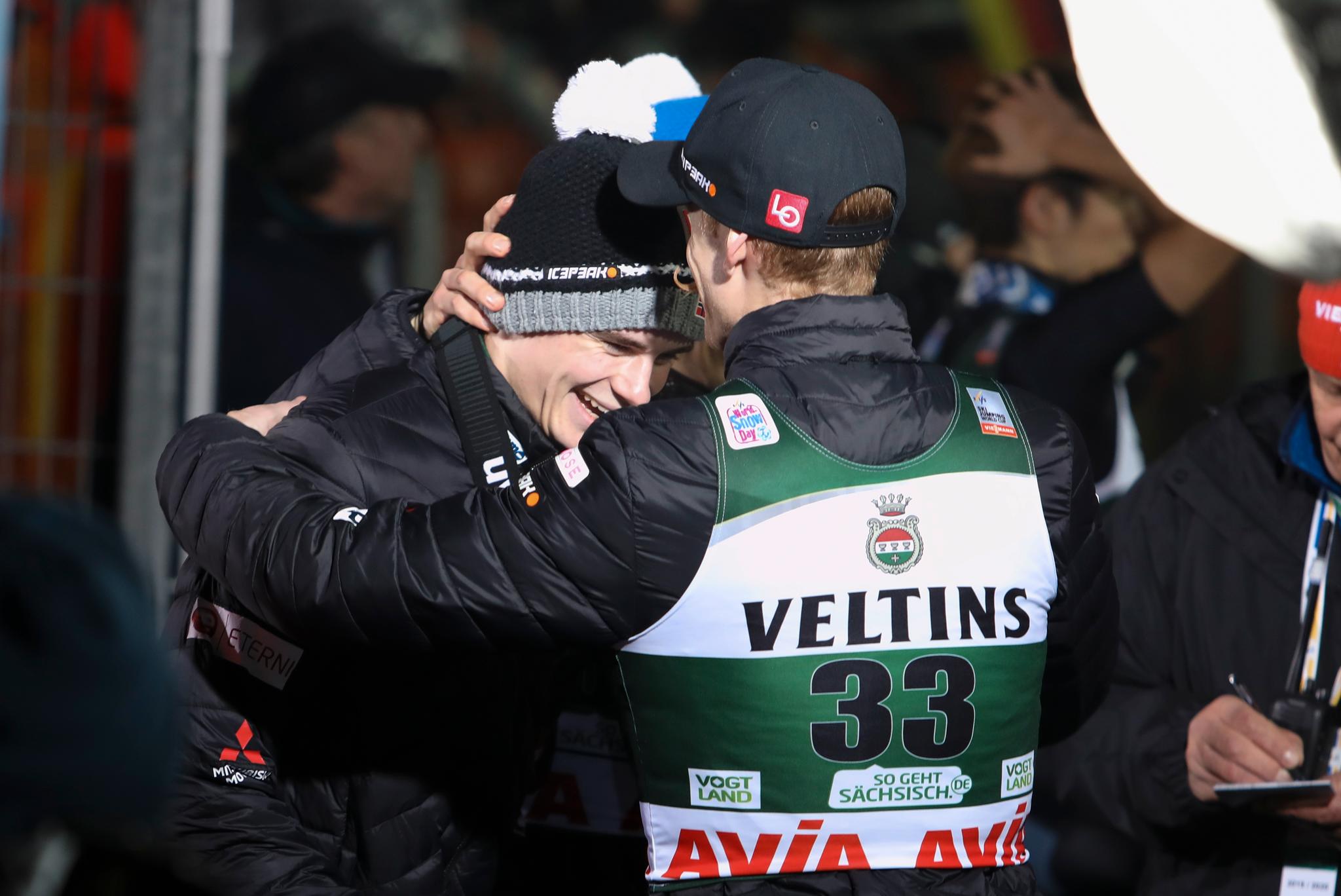 Marius Lindvik gratuleres av Robert Johansson etter en sterk prestasjon i verdenscuprennet i Klingenthal søndag.