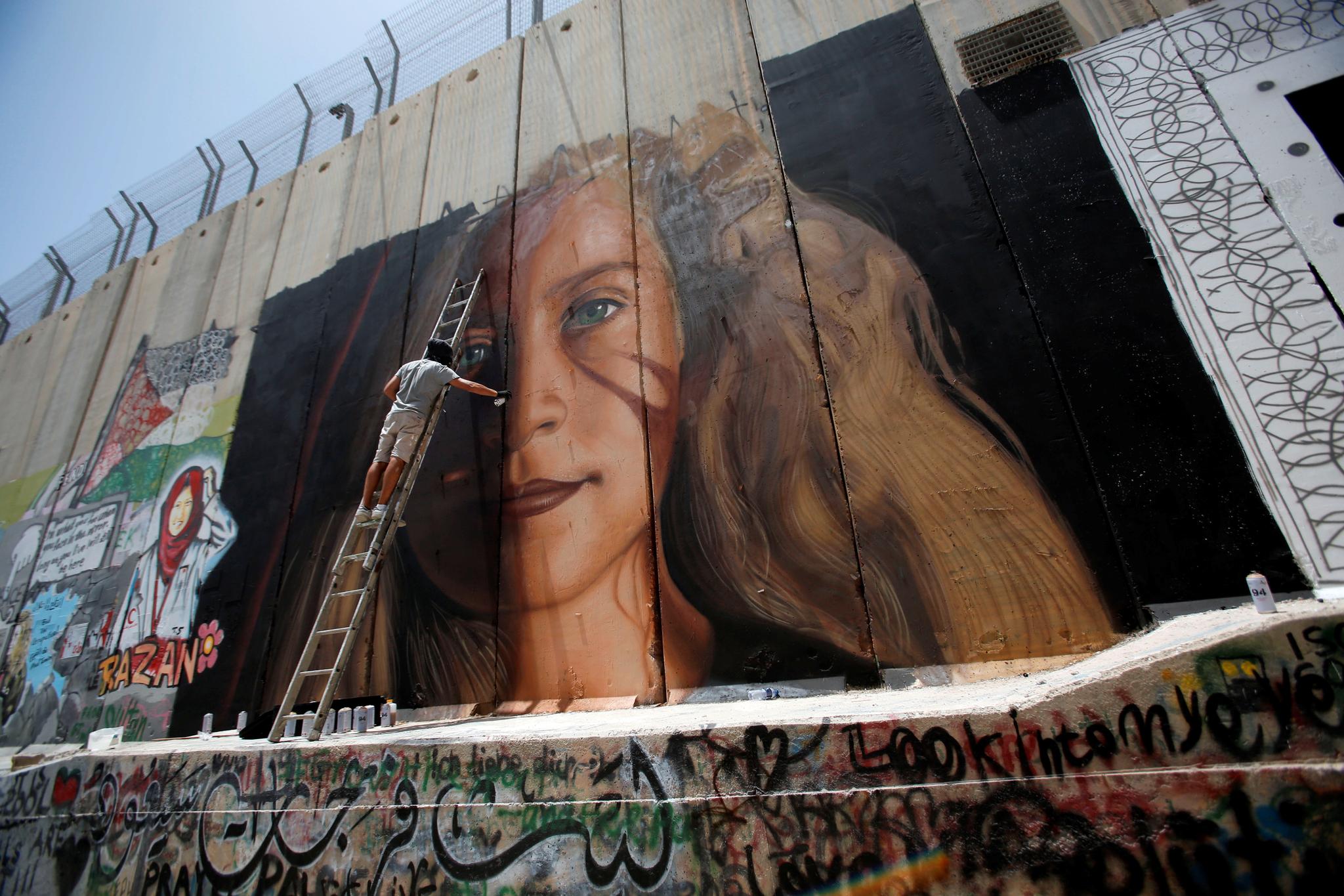 To italienske kunstnere ble kastet ut av Israel etter å ha malt dette maleriet av Ahed Tamimi på barrieren som omkranser vestbredden