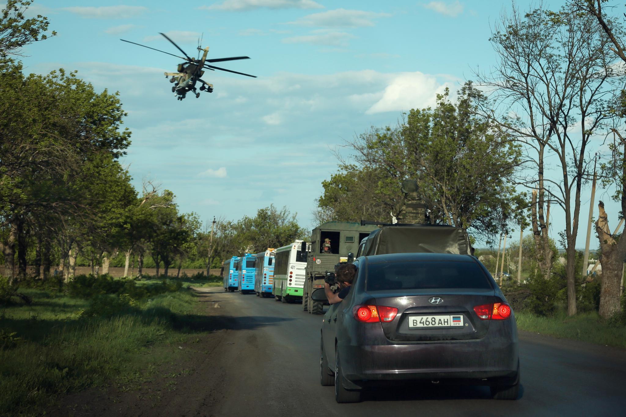 Et russisk helikopter henger over busser med ukrainske soldater fra stålverket i Mariupol som har overgitt seg. 