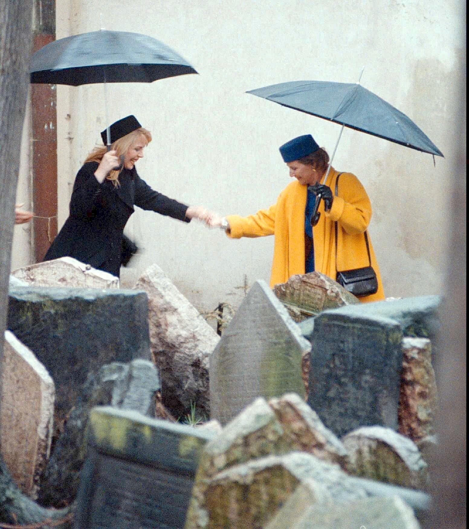 Dronning Sonja besøkte i 1997 den jødiske gravplassen i Praha der biter av gravstein skal fraktes dersom det dukker opp flere. Her hjelper dronningen Dagmar Havlova, konen til Vaclac Havel, Tsjekkias daværende president, over en sølepytt. 