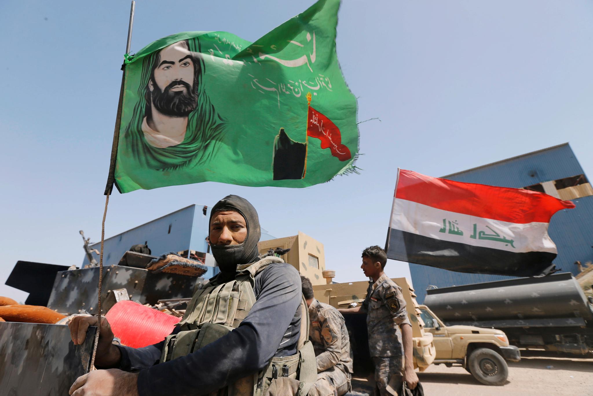 En sjiamuslimsk militskriger poserer med et religiøst flagg i utkanten av Falluja tirsdag.