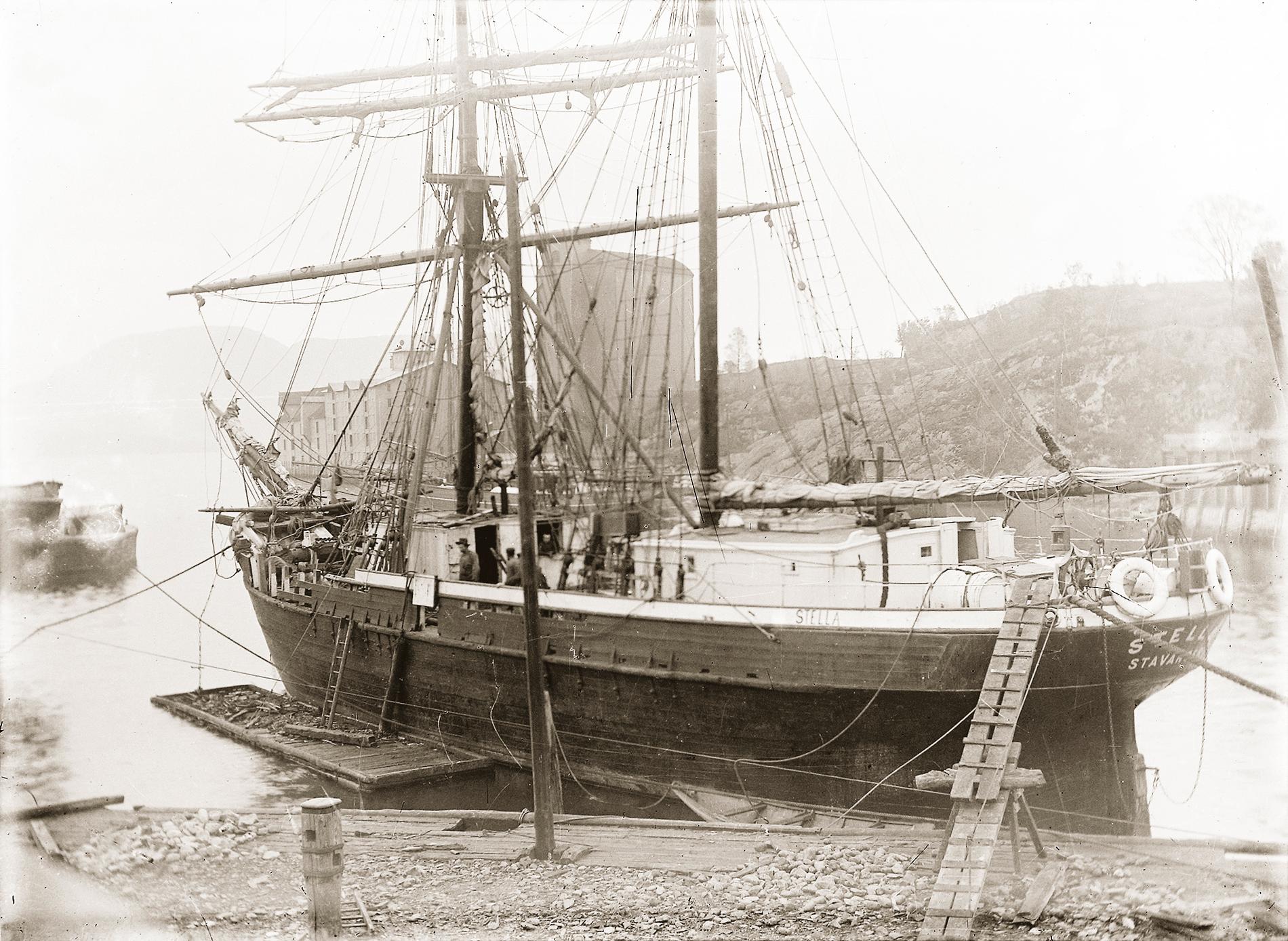 Seilfartøyet «Stella» av Stavanger under reparasjon. Langs skipssiden ligger en tømmermannsflåte.