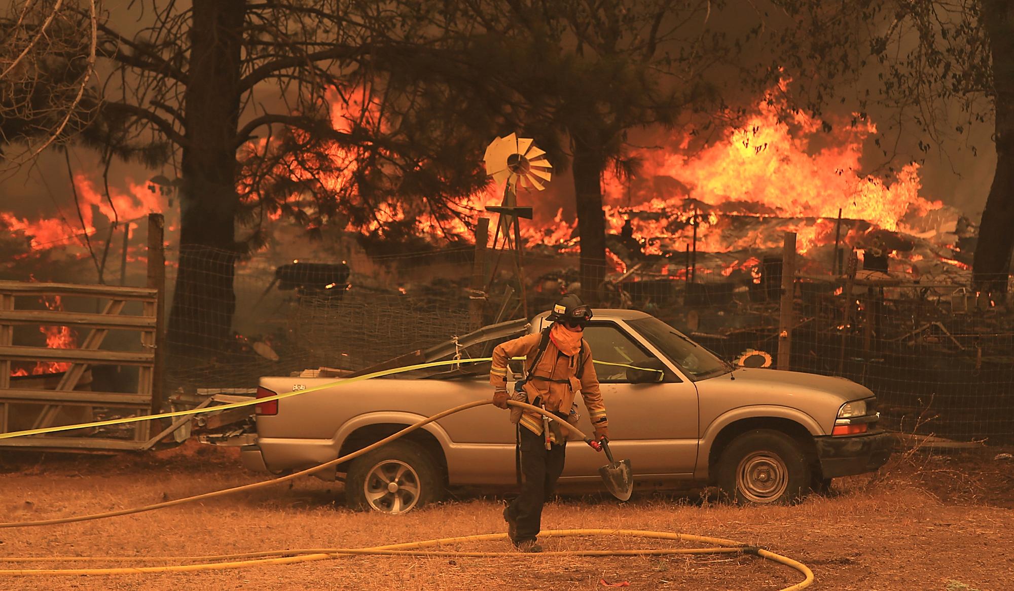 En brannkonstabel jobber med slukkingsarbeid foran en brennende bygning i Spring Valley.