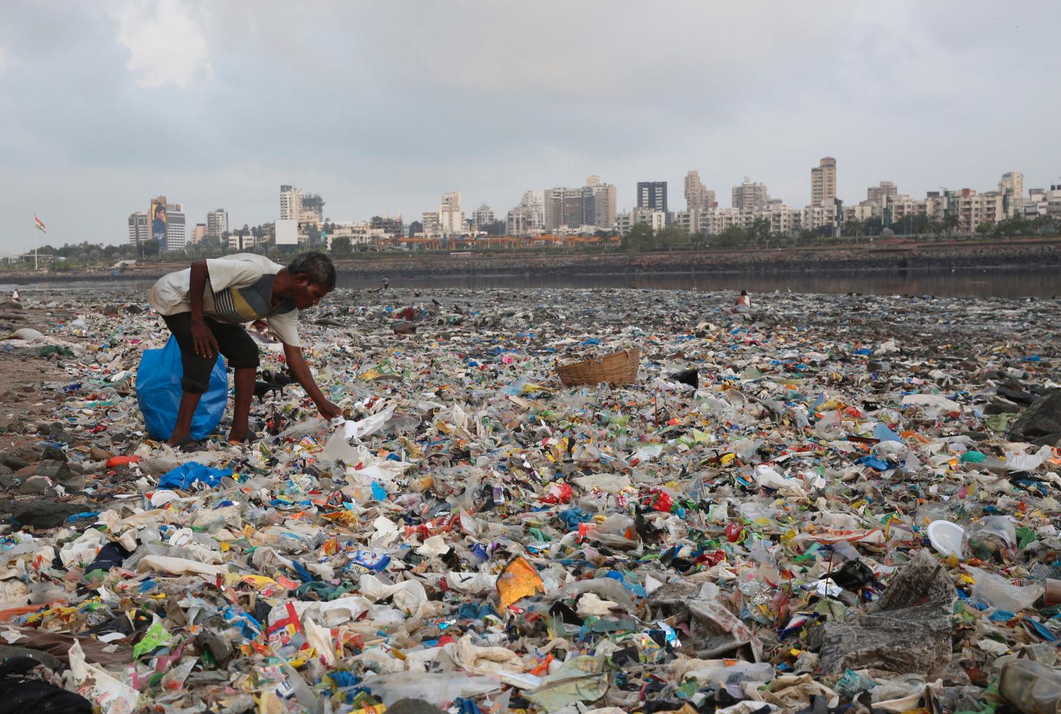 En mann samler inn plast og andre resirkulerbare materialer fra stranda langs Arabiahavet i Mumbai i India. Bildet er tatt 4. juni. 
