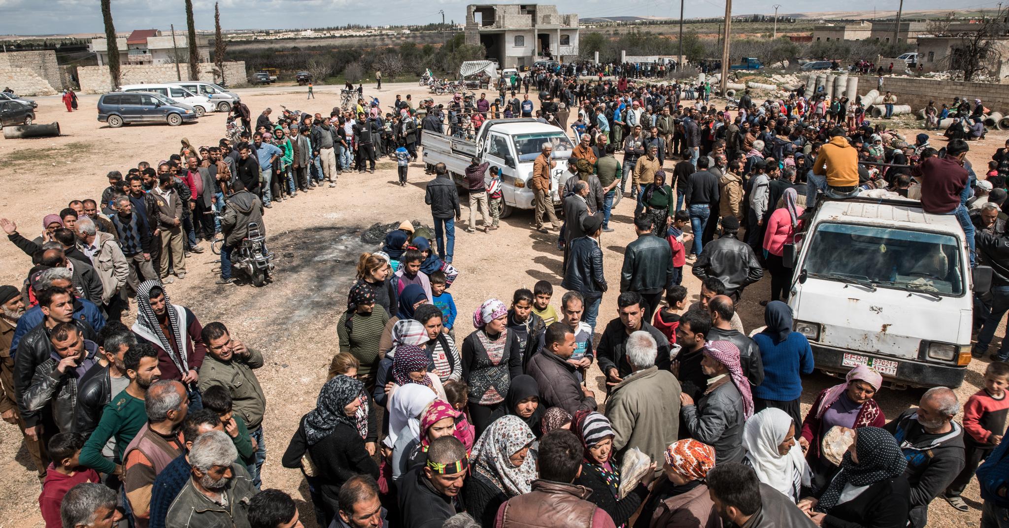 Tusenvis av flyktninger fra Afrin står i kø for å motta brød utenfor byen Tal Rifaat i Syria. Bildet er tatt i mars 2018.