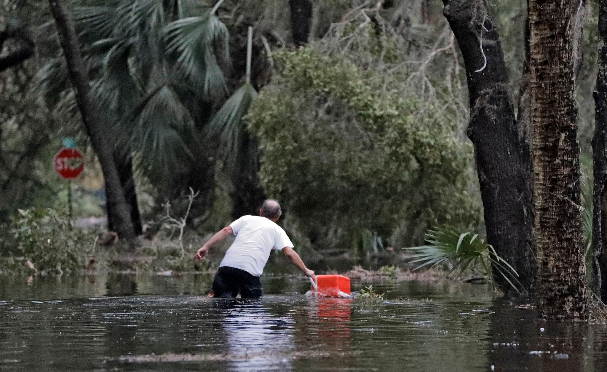 En mann trosser flomvannet i boligområdet sitt i St. Marks i Florida.