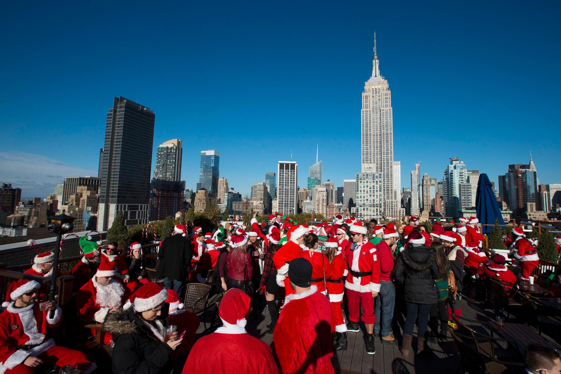 New York arrangerer årlig verdens største SantaCon. Her er noen av deltakerne på en takterrasse i 2014, i bakgrunnen ruver Empire State Building. 