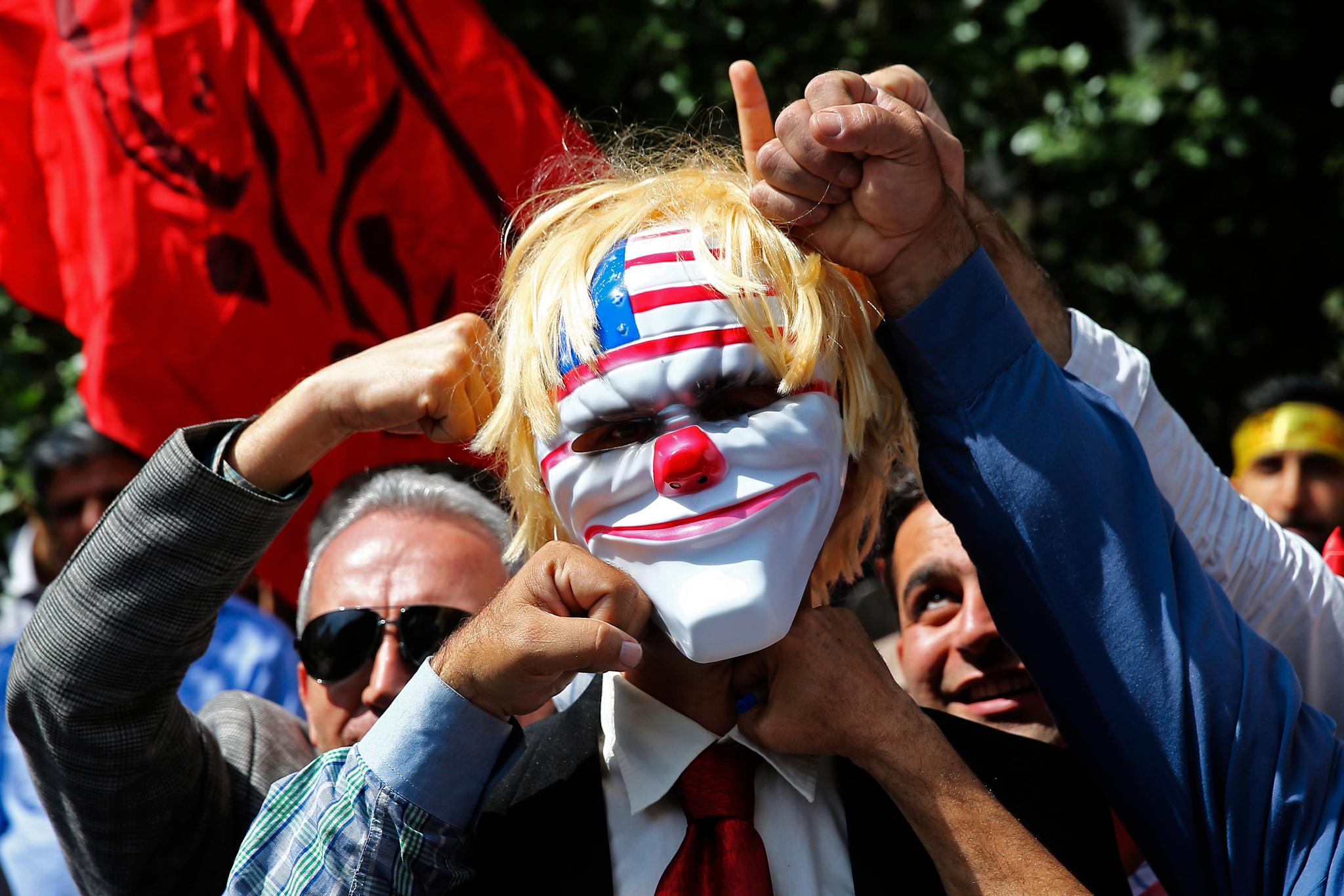 Motstanden mot USAs utenrikspolitikk har vært en viktig del av iranske myndigheters budskap de siste 40 årene. Her slår en iransk demonstrant til en maske som skal forestille Donald Trump under en protestaksjon utenfor den amerikanske ambassaden i Teheran i mai.
