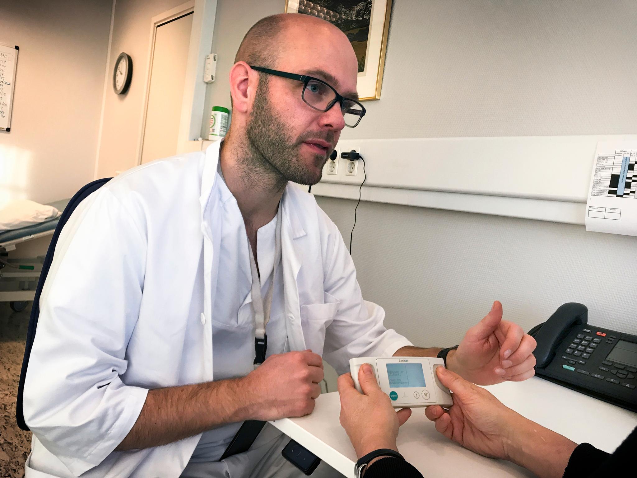 Doktorgradsstipendiat Trygve Berge forklarer en pasient hvordan hjerterytmen måles gjennom tomlene, signalene ble sendt direkte til Bærum sykehus,