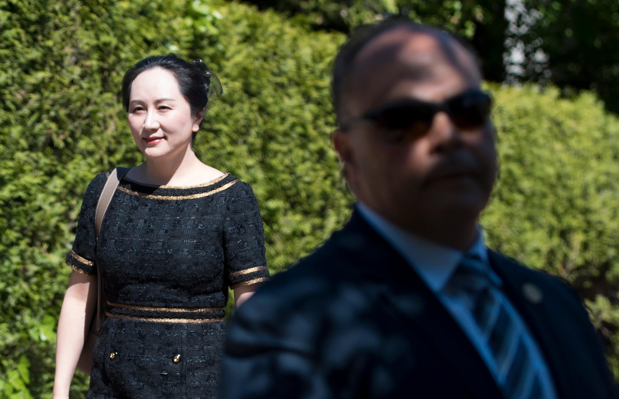 Den kinesiske teknologigiganten Huaweis finansdirektør Meng Wanzhou på vei til domstolen i Vancouver onsdag. I forgrunnen passer en sikkerhetsvakt på. 