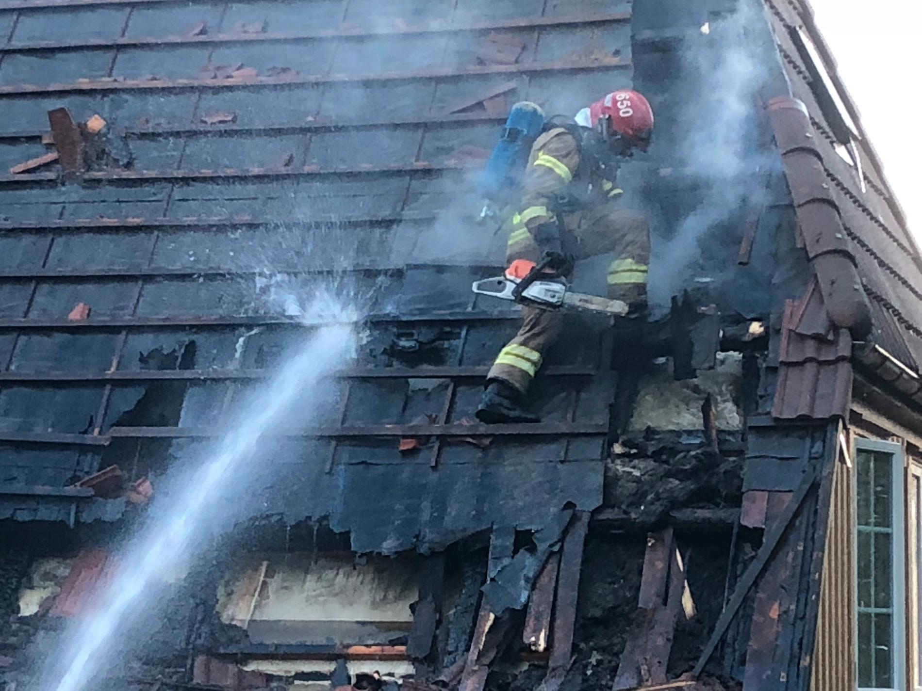 VANSKELIG: Brannmannskapene måtte fjerne takstein og sage hull i taket for å komme til flammene i firemannsboligen i Blodbyen. 